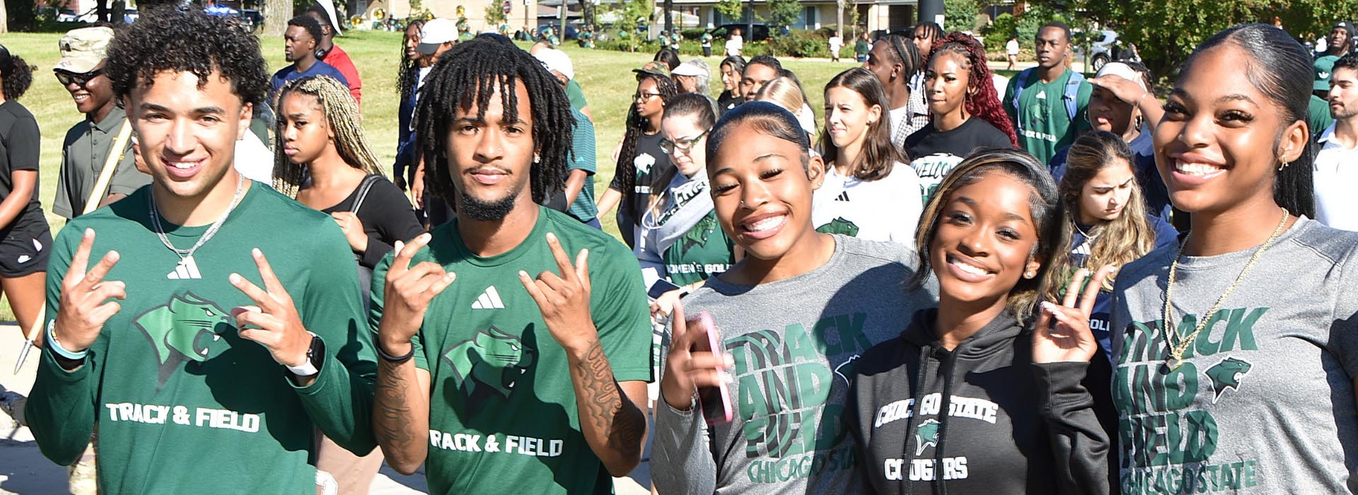 A group of student-athletes wearing Chicago State Track and Field apparel smile and pose together outdoors during a campus event.