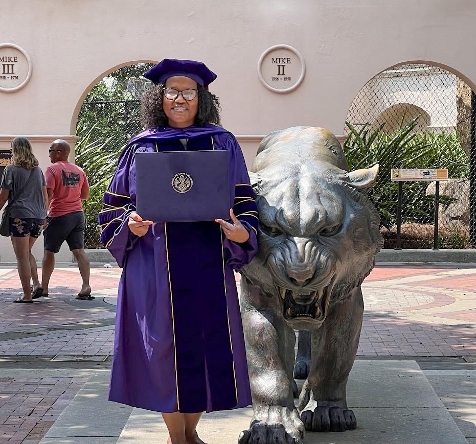 PhD graduate standing with diploma.