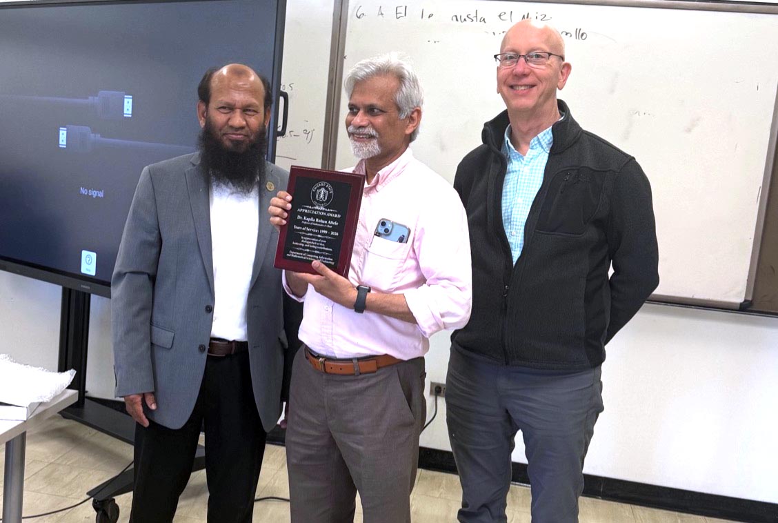 Dr. Attele smiles while holding a plaque while CIMST chair Dr. Salam and Dean Mark Smith (College of Arts and Science) smile and stand alongside him.