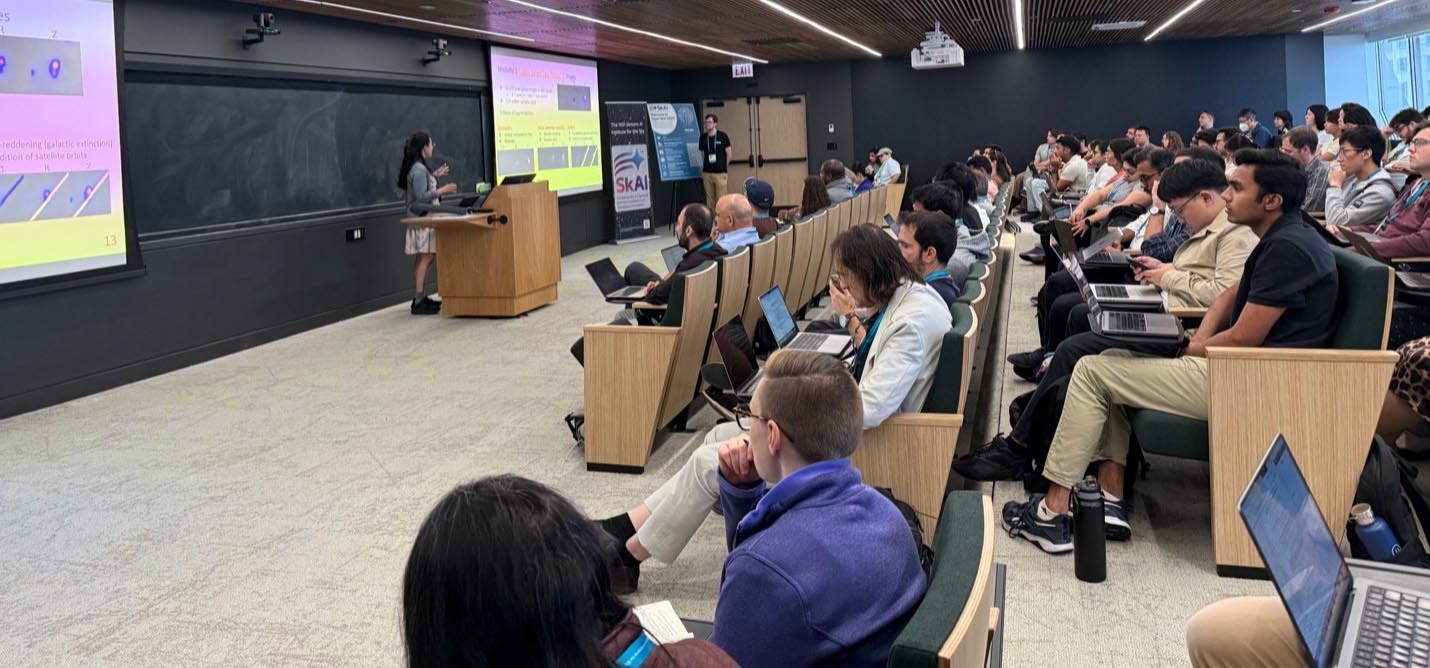 Attendees of the skAI Conference sit audience-style in a large, modern conference room while a speaker at a podium presents.