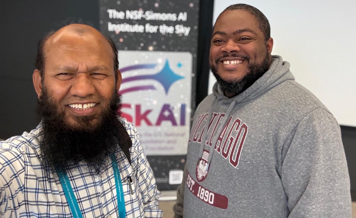 Dr. Salam poses for a selfie with a student wearing a gray University of Chicago hoodie.