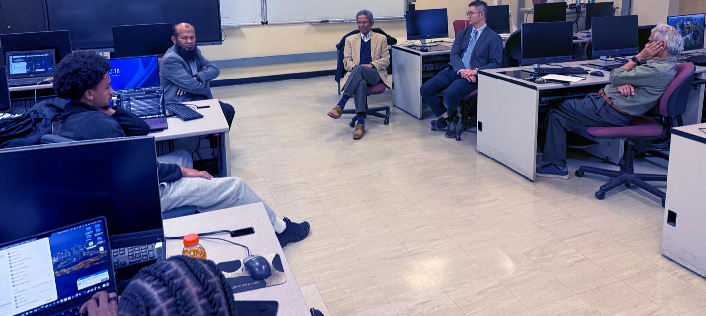 A group of people sitting in a computer lab having a discussion