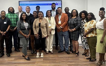 A group of seven adults standing and smiling in the lobby of Elgin Community College